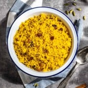 Easy yellow rice with raisons in a whilte bowl.