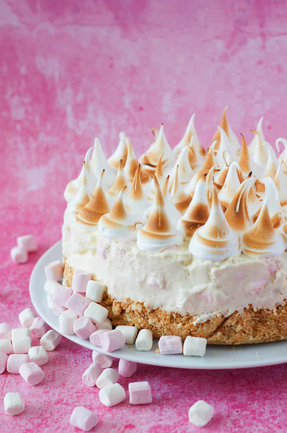 Marshmallow tart on a white plate with peaks of piped marshmallow fluff on top