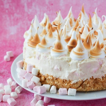 Marshmallow tart on a white plate with peaks of piped marshmallow fluff on top