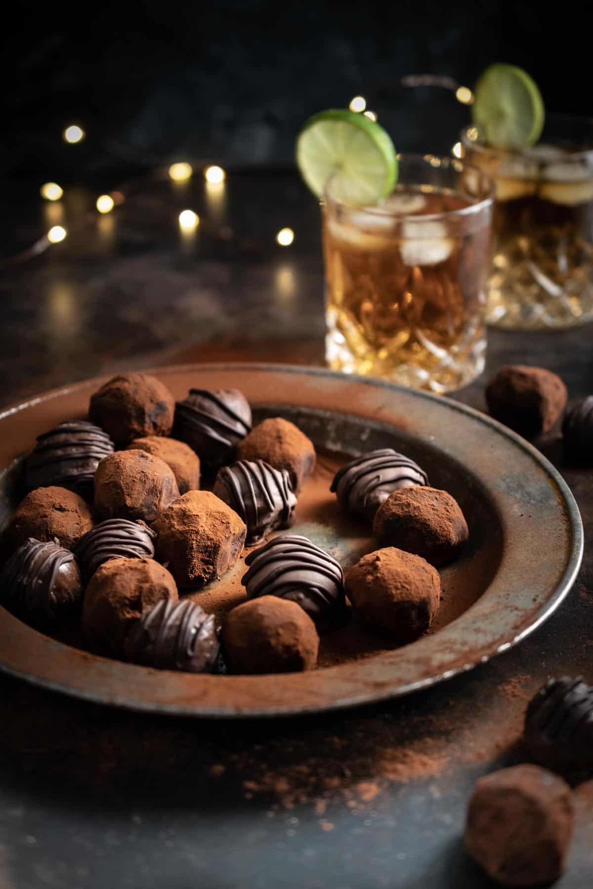 Rum and ginger truffles on a metal plate with a dark and stormy cocktail in the background