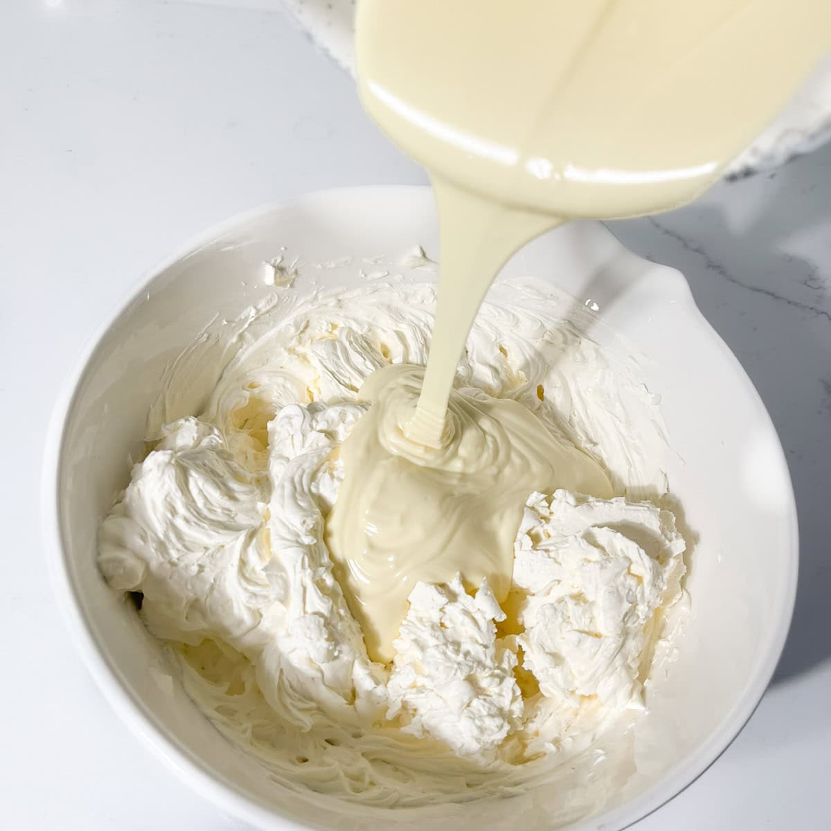 Adding the melted white chocolate to the cream, cream cheese and mascarpone for the no bake cheesecake.