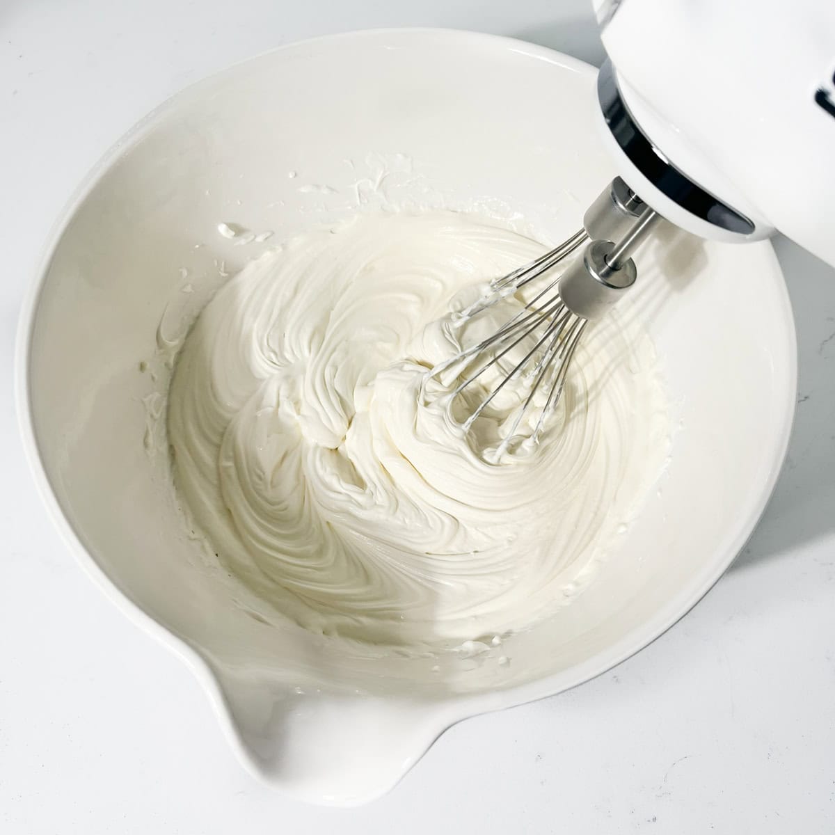 Whipping cream to soft peaks for the strawberry and white chocolate cheesecake.