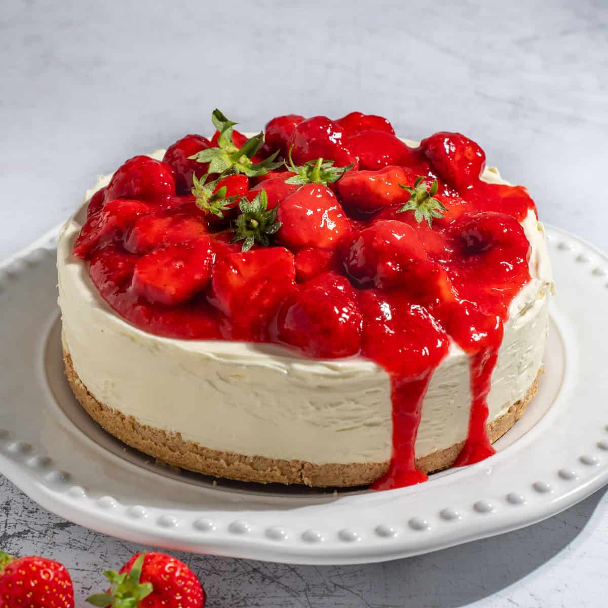 A strawberry and white chocolate cheesecake on a large white plate.