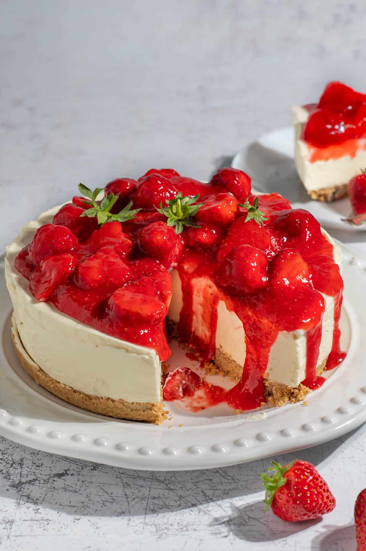 A strawberry and white chocolate cheesecake on a large white plate.
