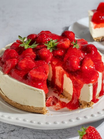 A strawberry and white chocolate cheesecake on a large white plate.