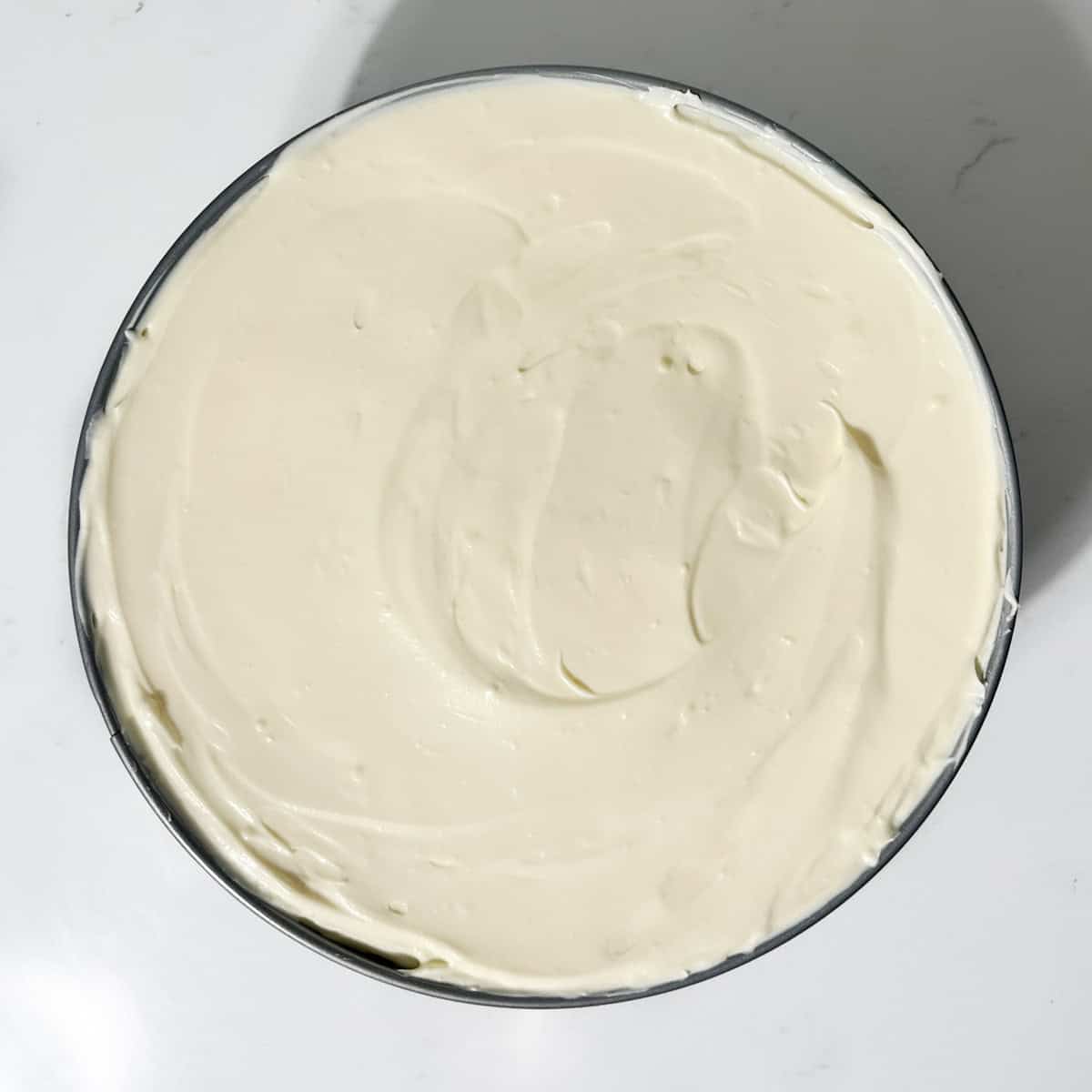 White chocolate cheesecake filling in a springform baking tin, ready to go into the fridge.