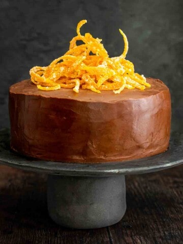 Chocolate orange cake on a grey cake stand with orange peel decoration.