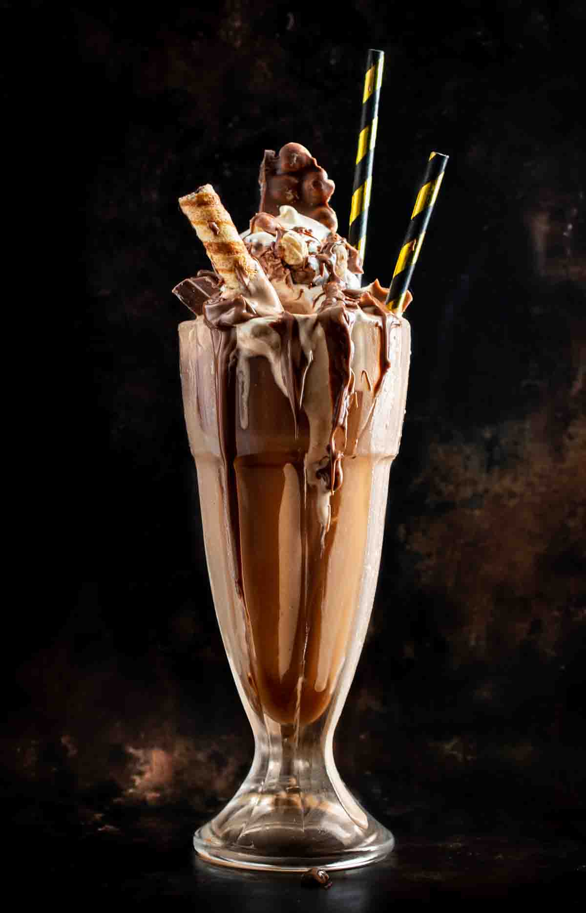 Nutella milkshake in a milkshake glass on a dark background.