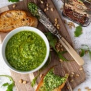 Rocket pesto in a bowl surrounded by slices of toasted ciabatta.