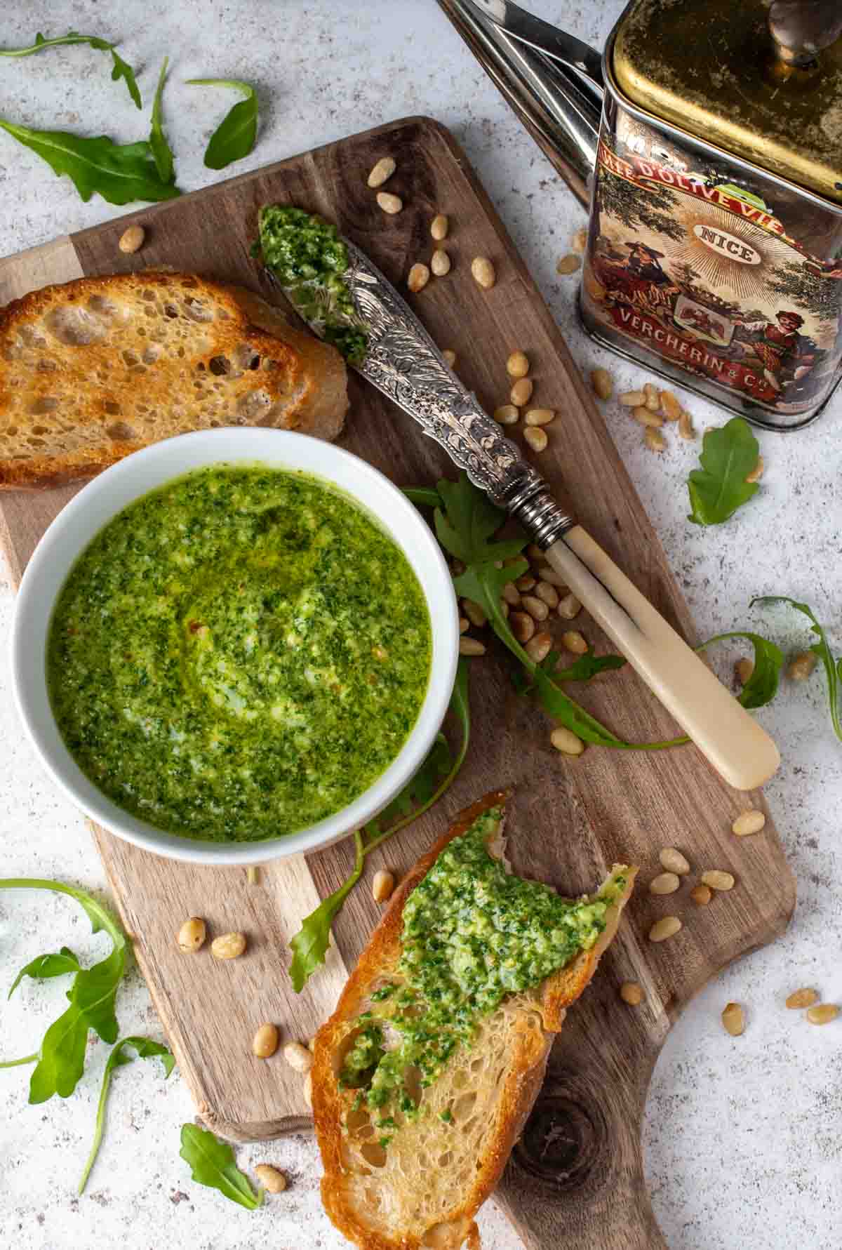 Rocket pesto in a bowl surrounded by slices of toasted ciabatta.