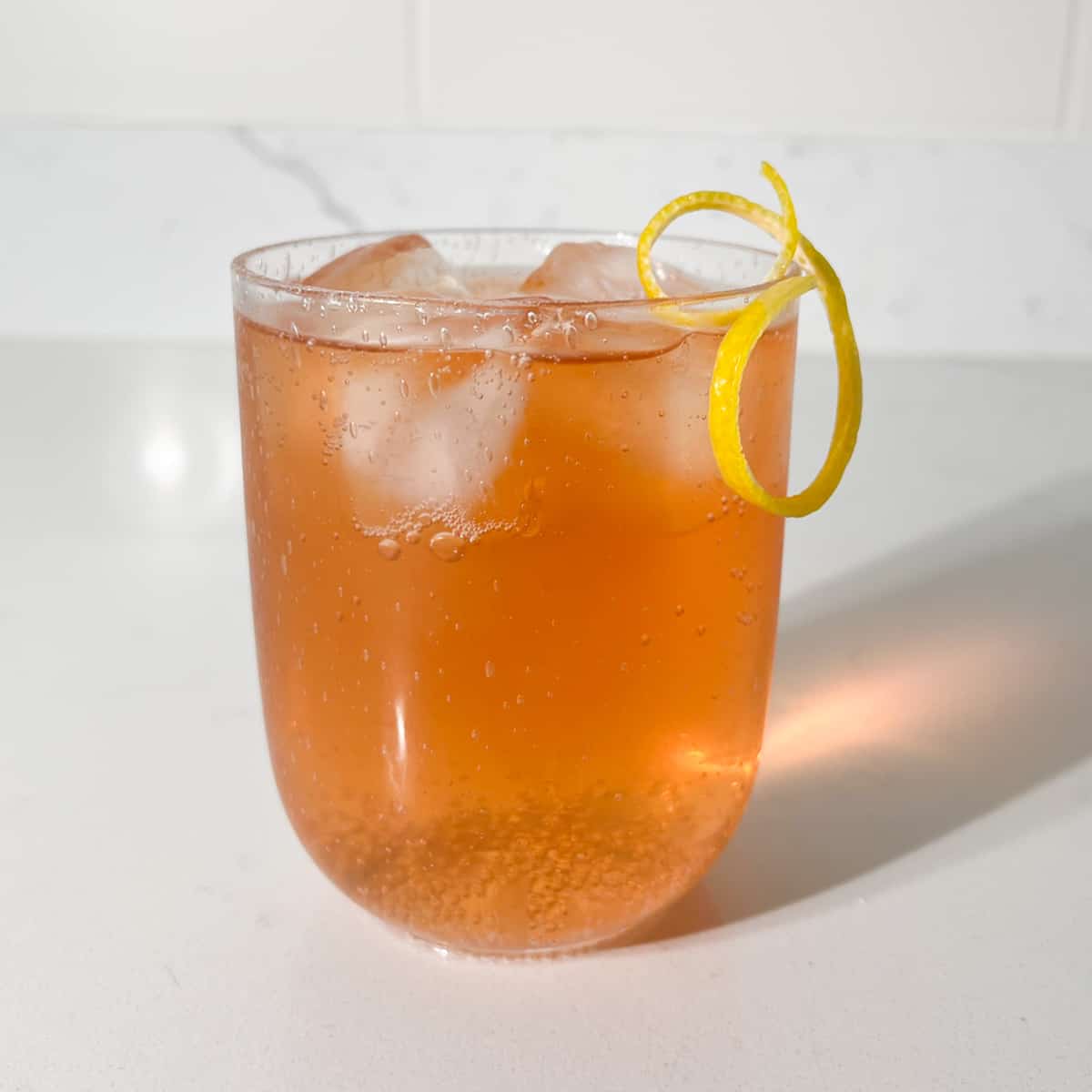 A glass of completed rock shandy with a lemon peel twisty.