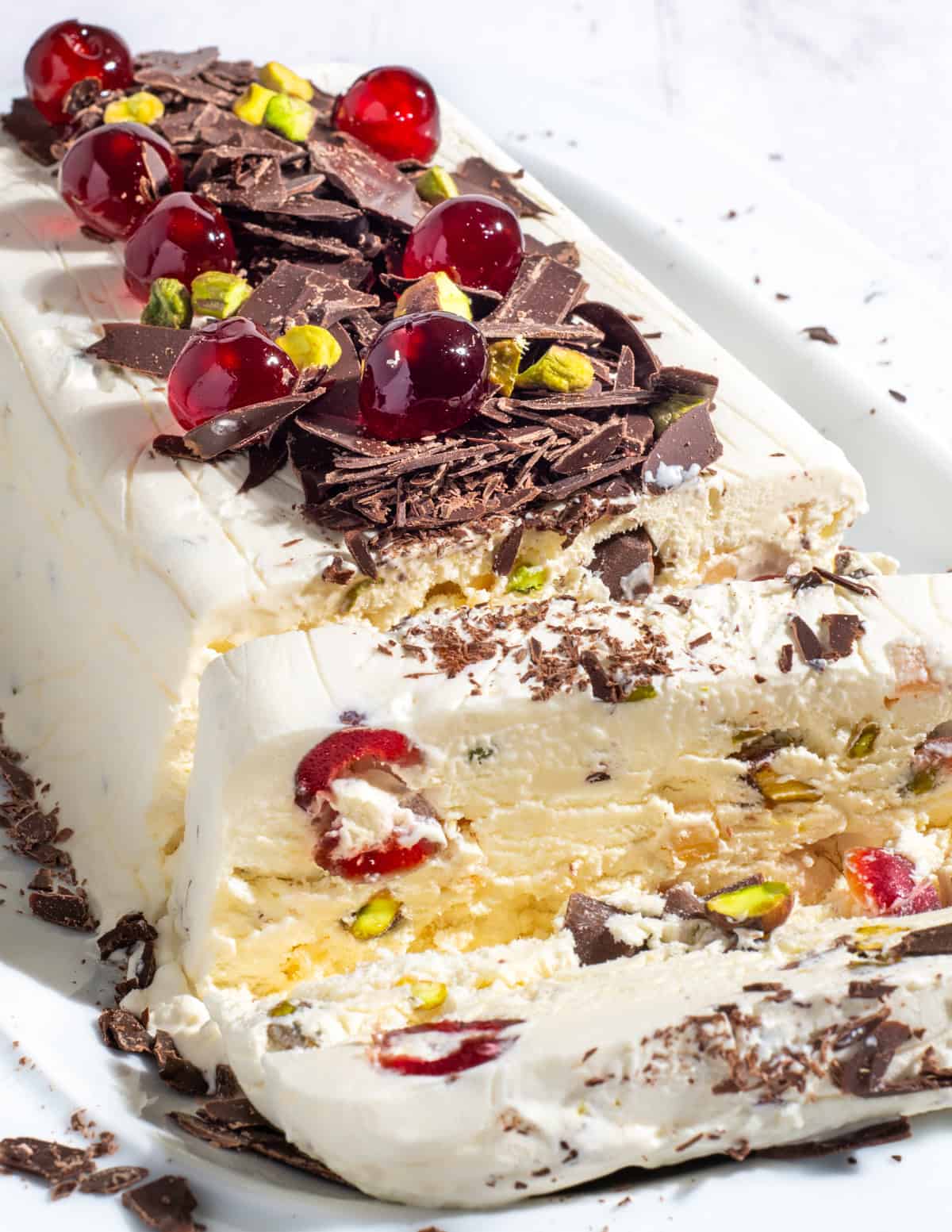 Cassata ice cream loaf showing a slice of ice cream with cherries, pistachios and chocolate shavings.