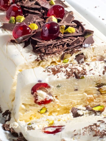 Cassata ice cream loaf showing a slice of ice cream with cherries, pistachios and chocolate shavings.