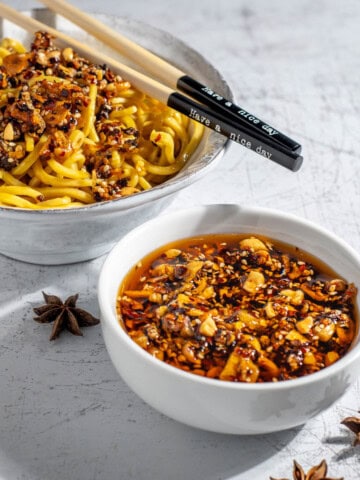 A bowl of crispy chilli oil alongside a bowl of egg noodles.