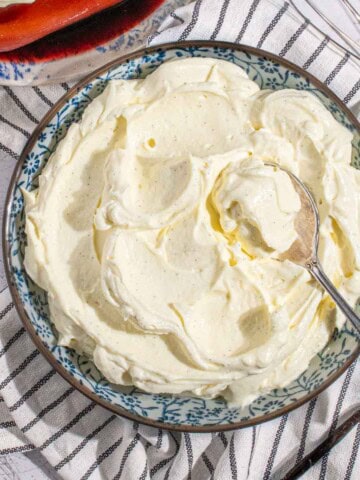A bowl of mascarpone cream next to a bowl of poached pears.