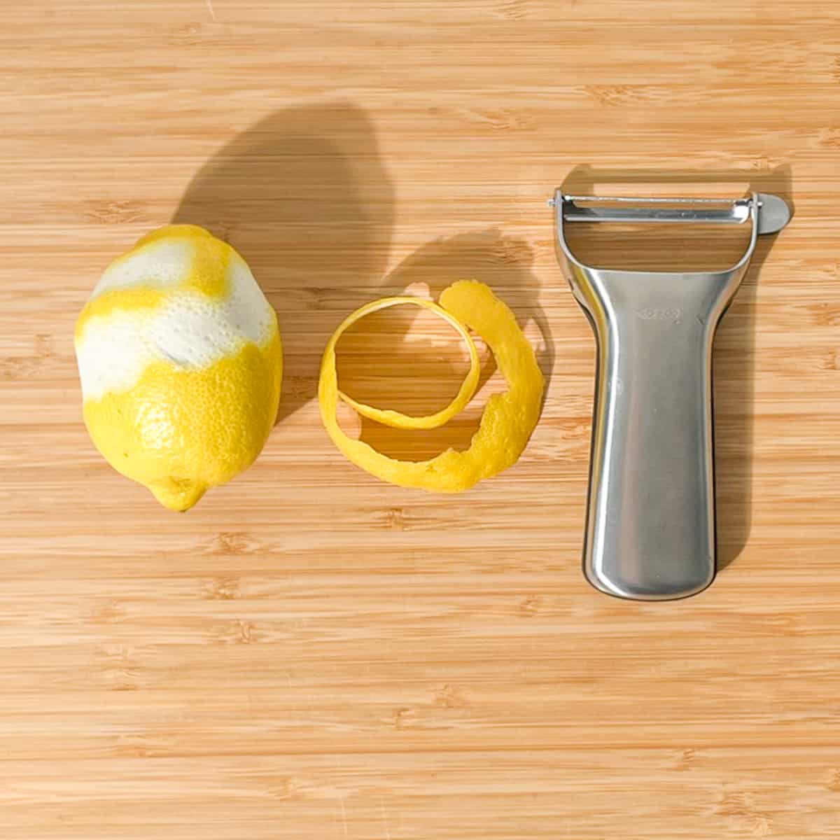 Peeling a long length of lemon peel with a peeler.