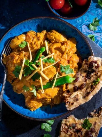 Chicken Karahi in a blue bowl with a torn piece of naan.