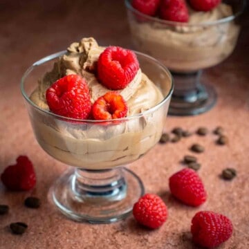 Two bowls of coffee mousse with raspberries on top.