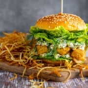 An ultimate fish finger sandwich on a wooden board with a side of shoestring fries.