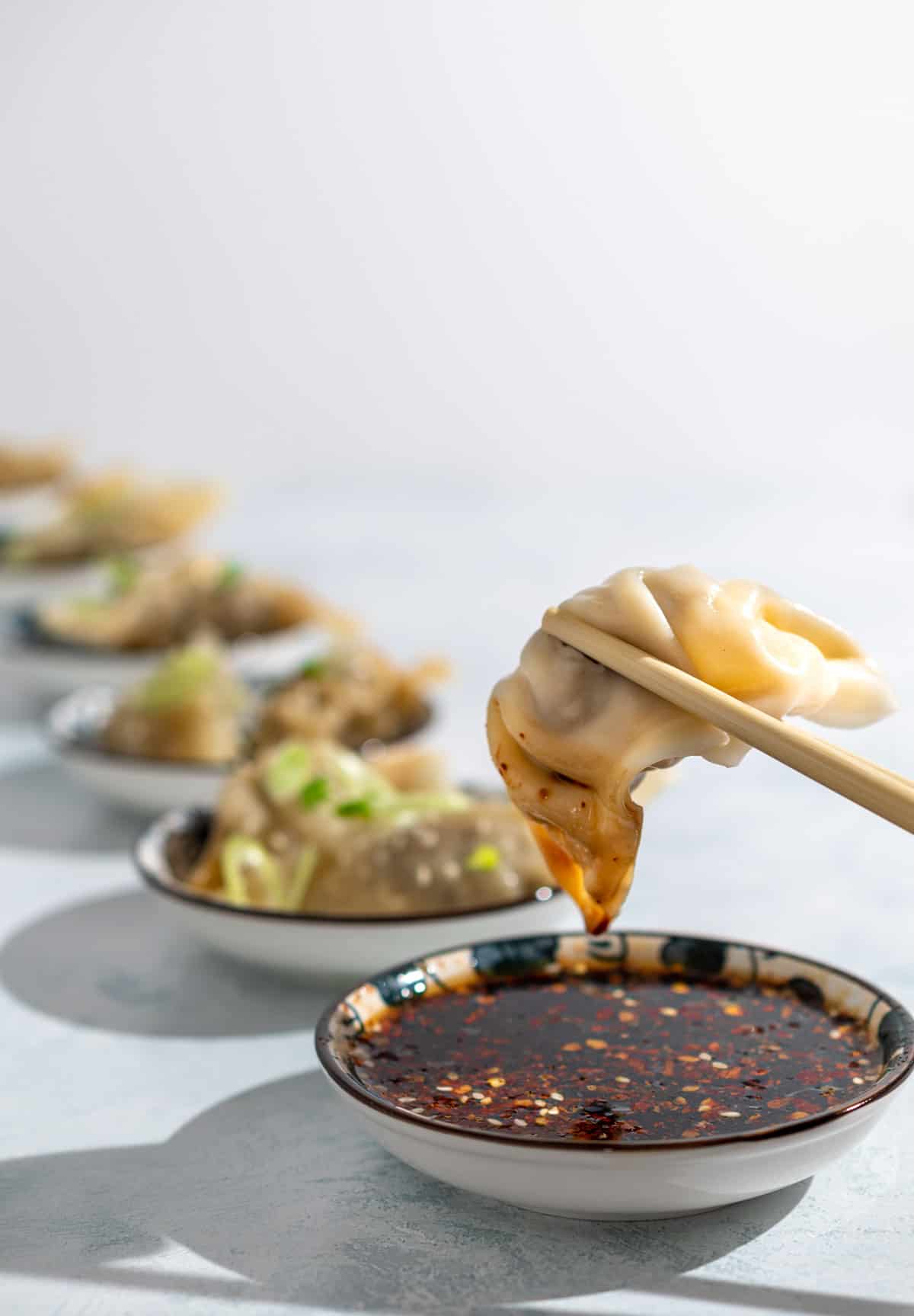 Gyoza sauce in a bowl with a Goyza dumpling being dipped into it.