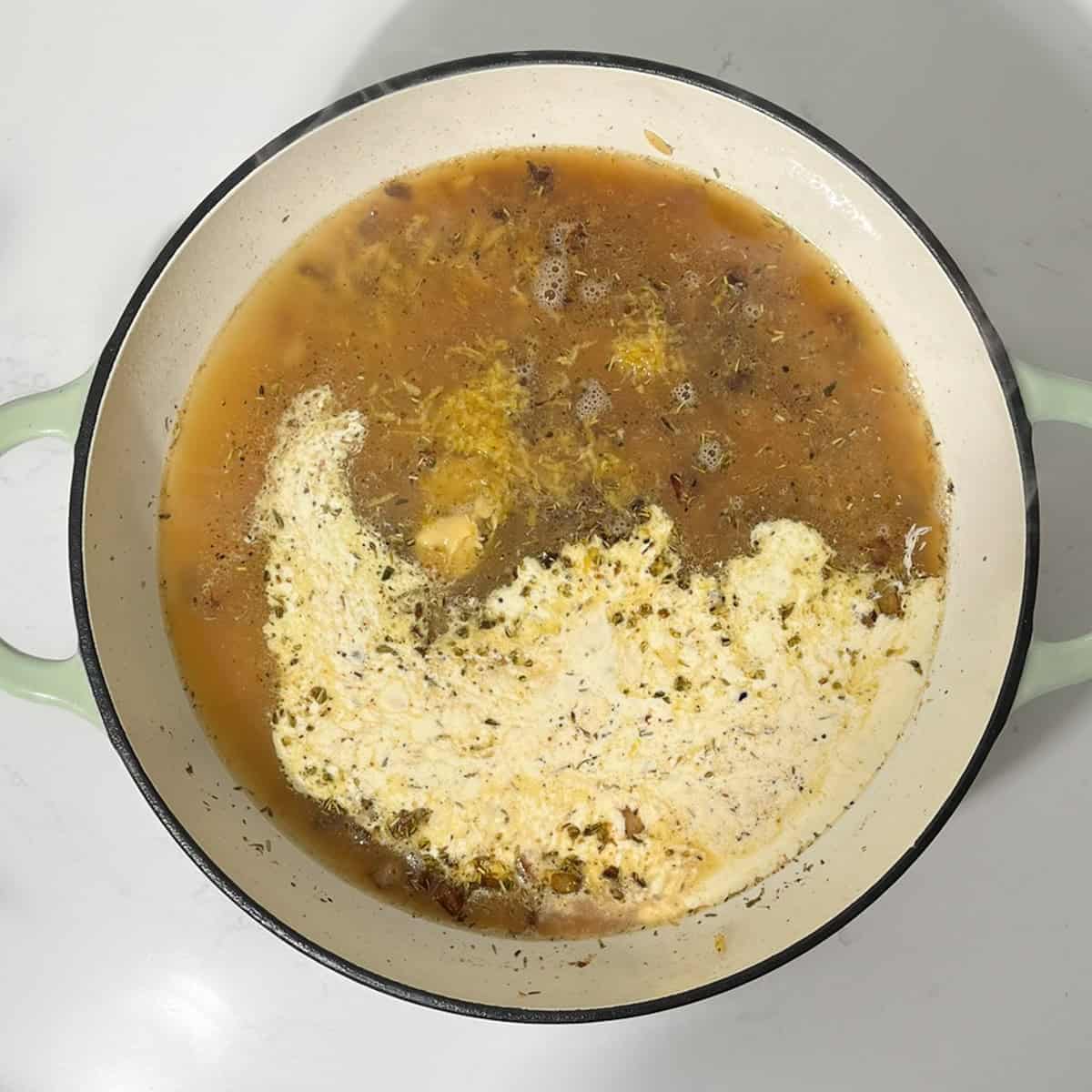 Adding chicken stock and cream to the toasted orzo.