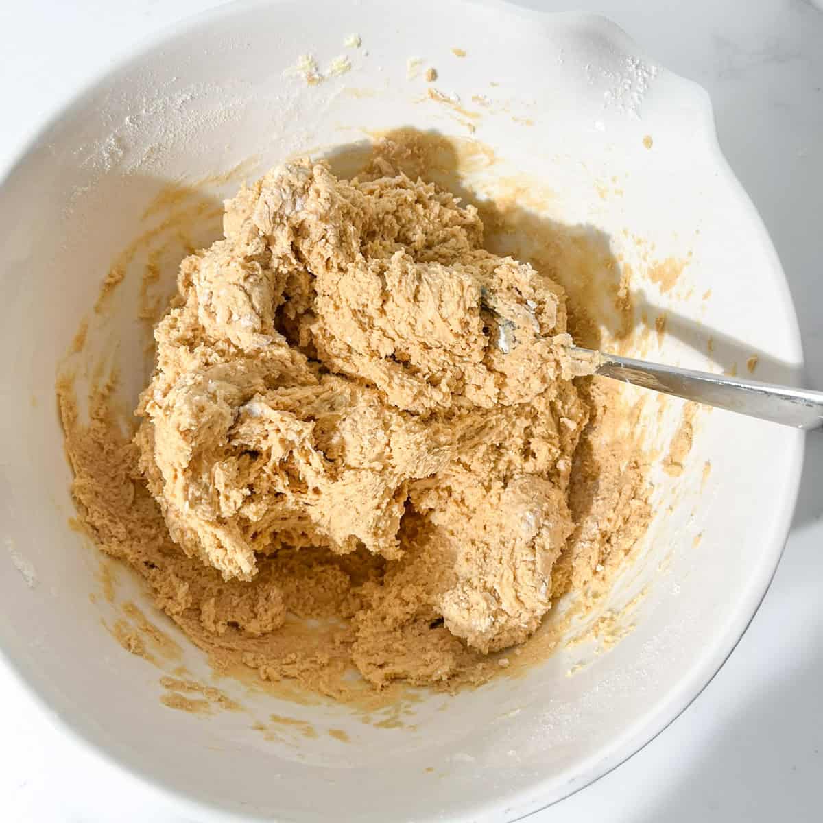 Caramel cookie dough mixed until combined in a white mixing bowl.