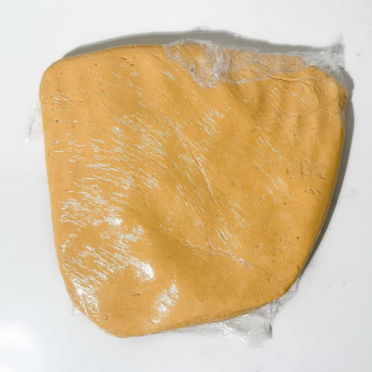 Caramel condensed milk cookie dough flattened and wrapped in cling film before chilling.