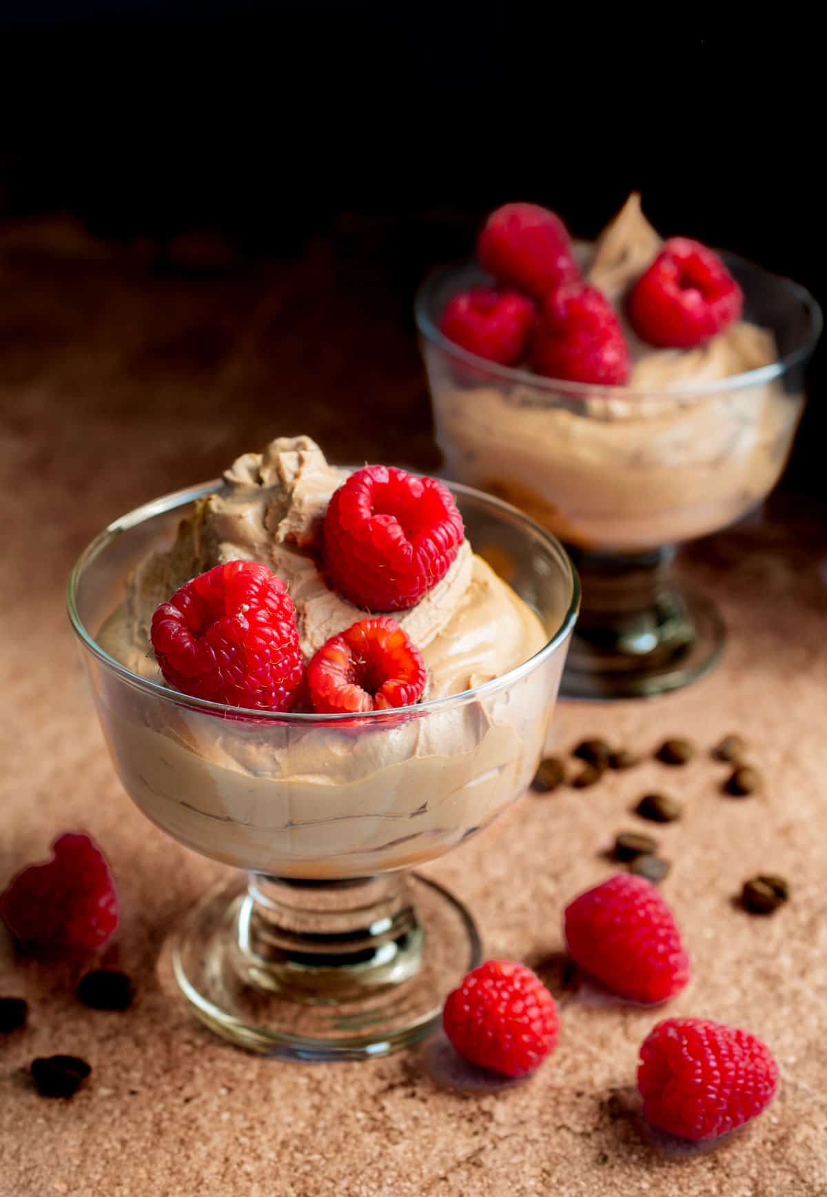 Coffee mousse in tow pudding bowls, topped with raspberries. 