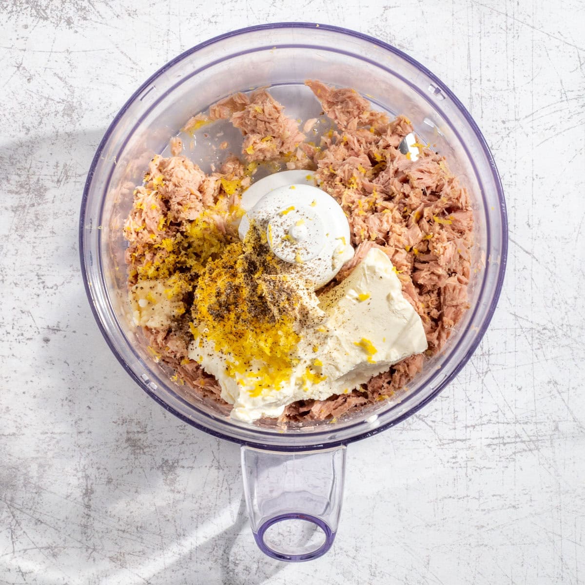 The unblended ingredients for tuna pate in the bowl of a food processor.