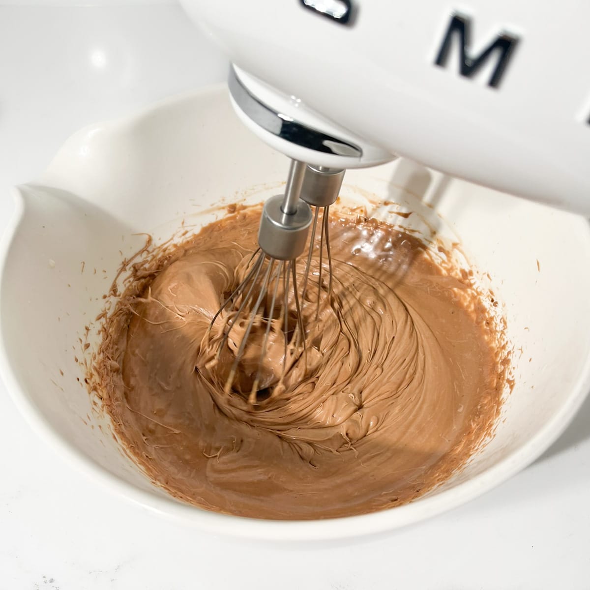 Whisking the mousse into soft peaks with an electric hand mixer