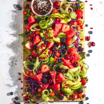 Rainbow salad on a wooden board and a white background.