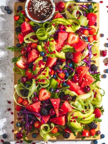 Rainbow salad on a wooden board and a white background.
