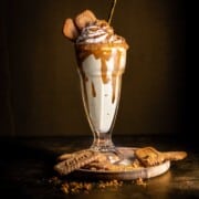 Biscoff milkshake in a milkshake glass, decorated with whipped cream and Lotus cookies.
