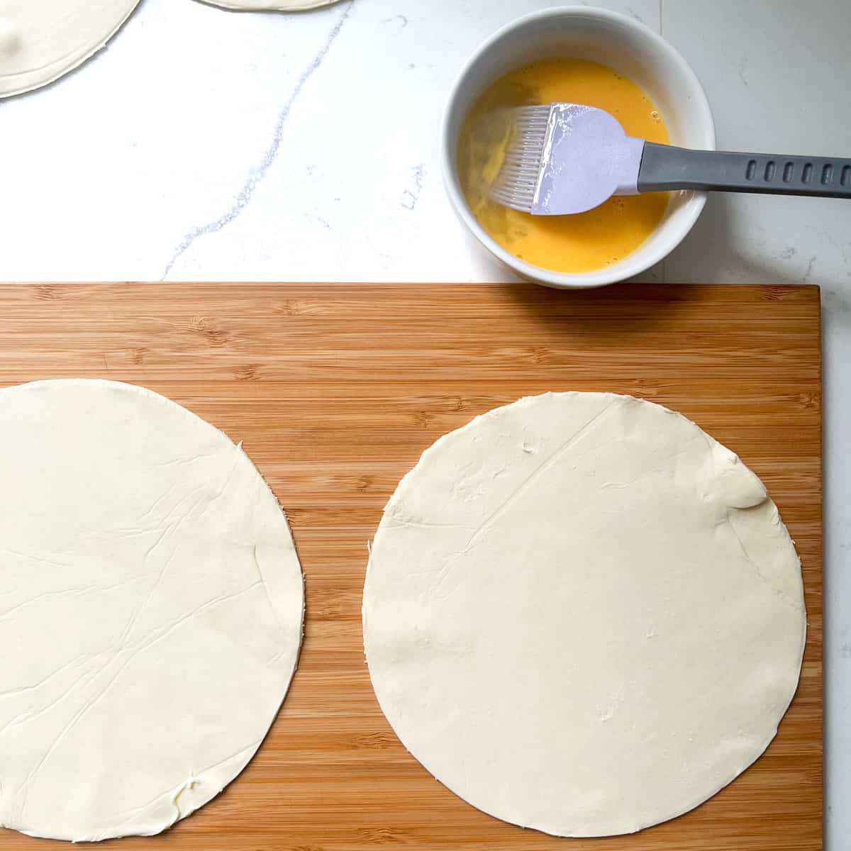 Cut out pastry circles on a wooden chopping board.