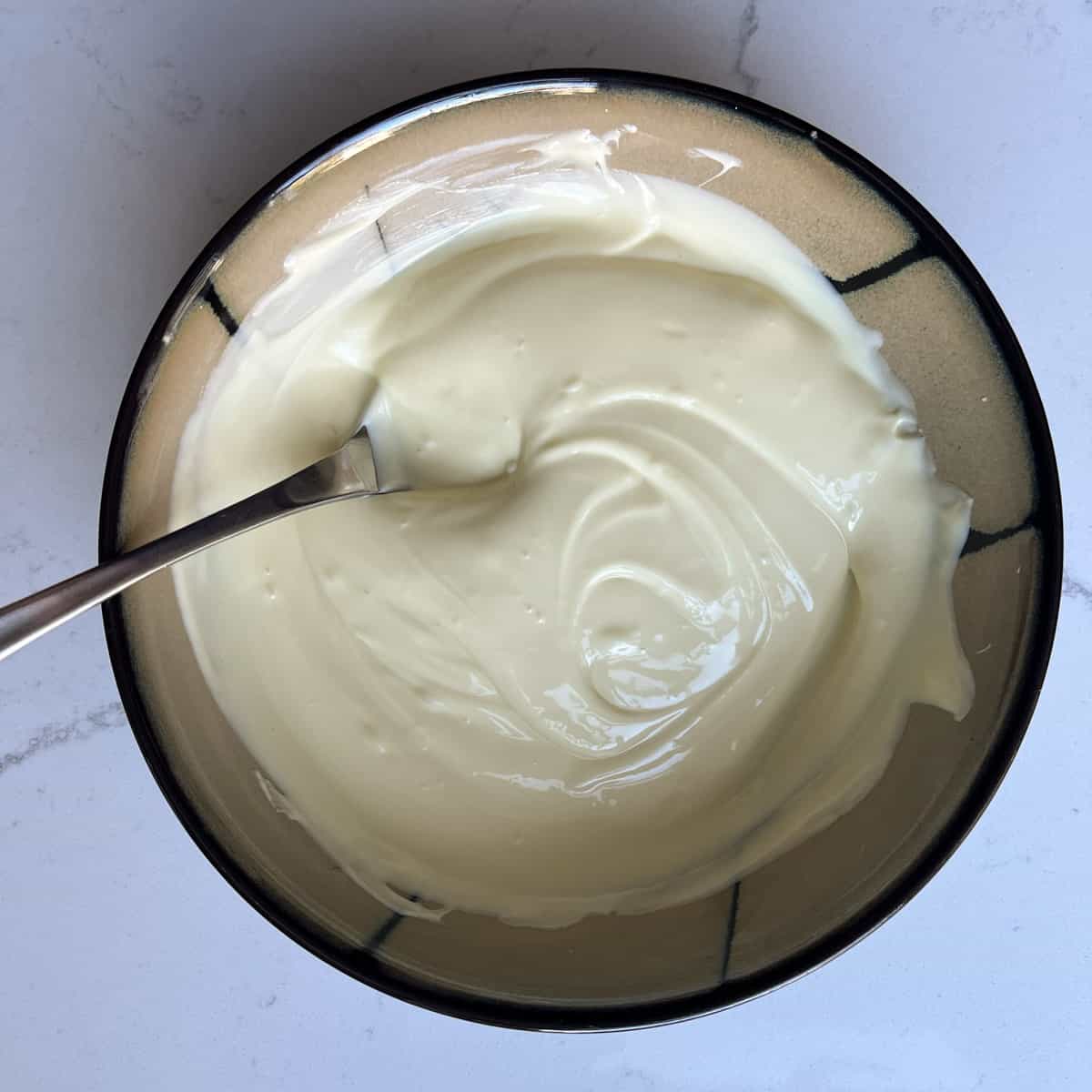 Milkybar cheesecake process - stirring a bowl of melted chocolate.