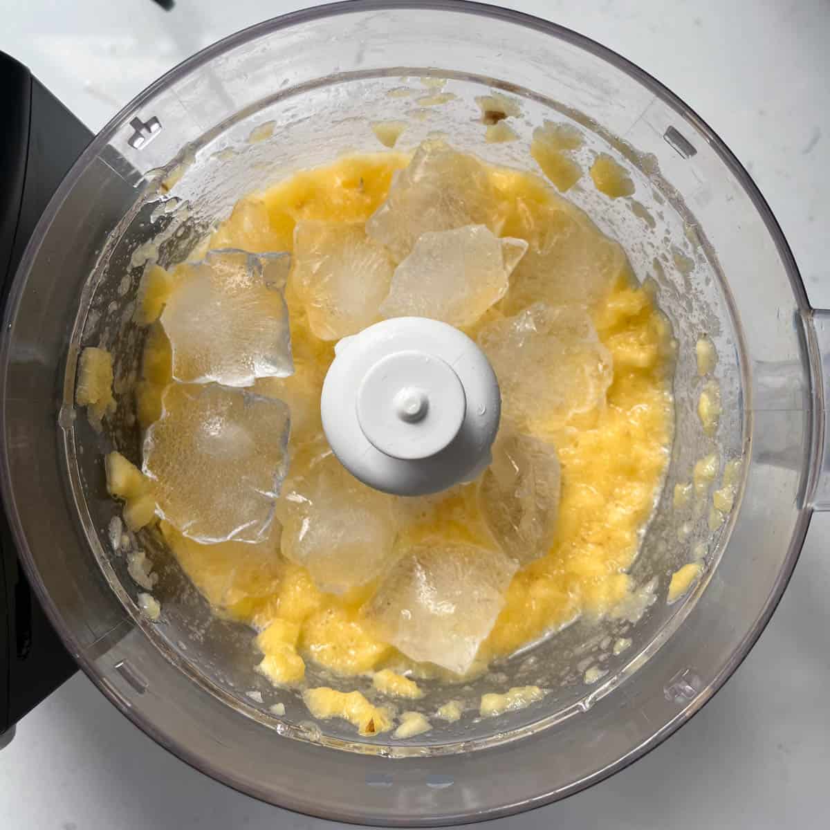Pineapple slushie adding ice to the blender.