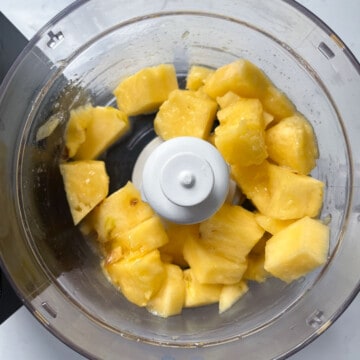 Pineapple slushie adding pineapple and honey to blender.