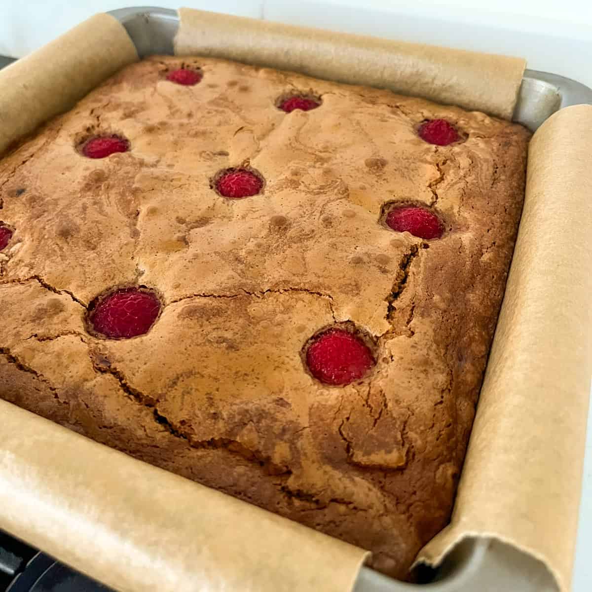 Baked raspberry and white chocolate blondies in a square pan.
