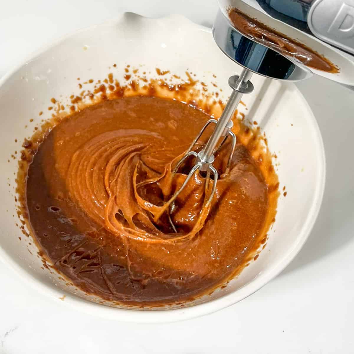 Beating all the liquid ingredients in a large white bowl.
