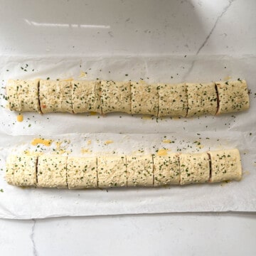 Chicken sausage rolls sliced, brushed with egg wash and sprinkled with sesame seeds and parsley.