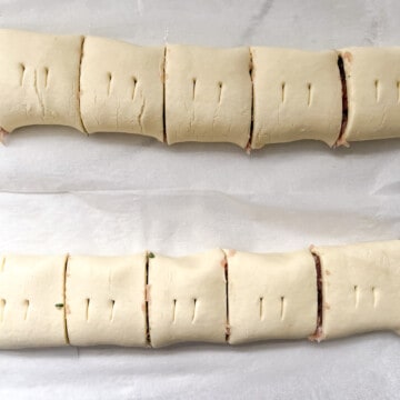 Chicken sausage rolls slices into portions and each roll stabbed with two small holes in the top.
