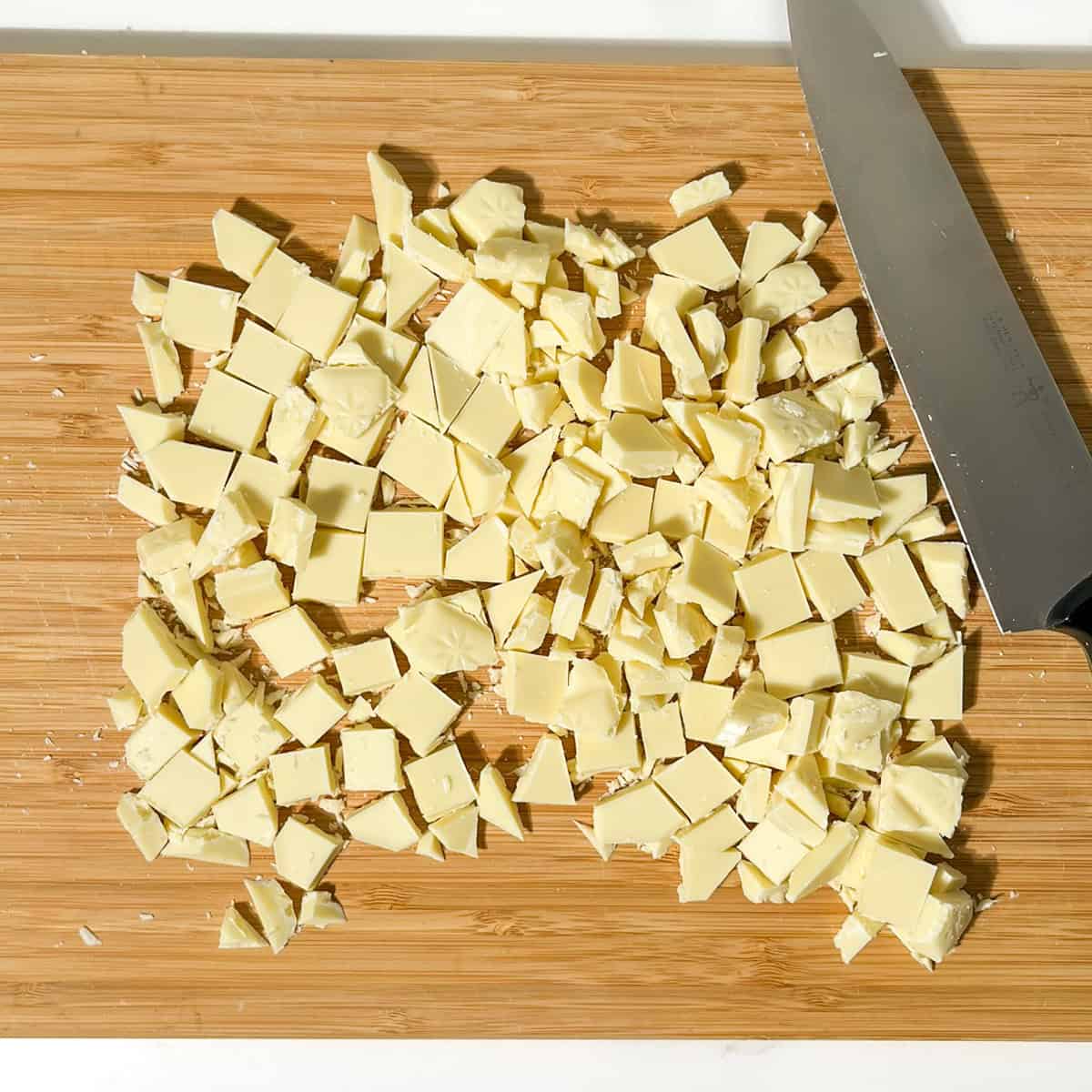 Chopped white chocolate on a wooden board.