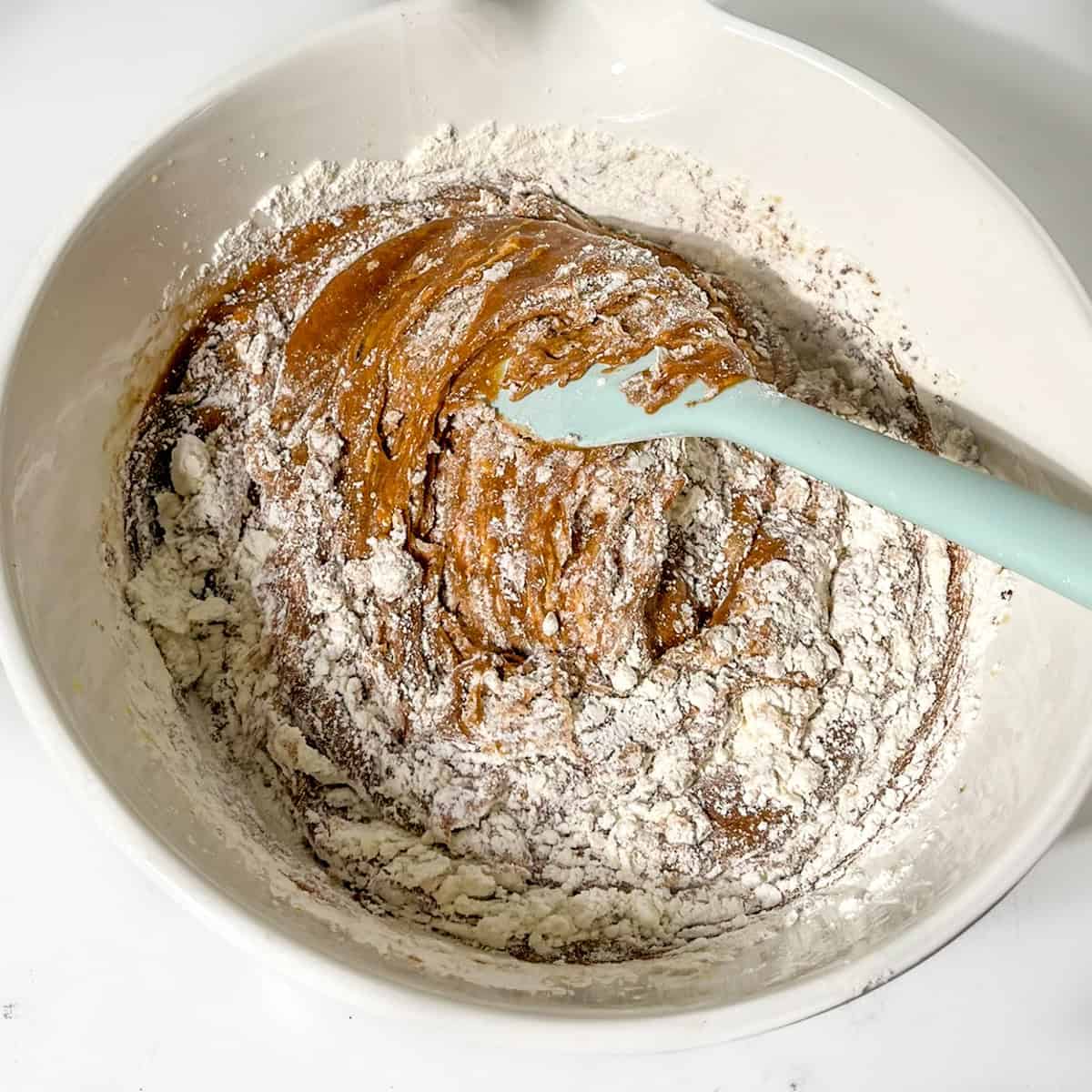 Folding dry ingredients into wet ingredients.
