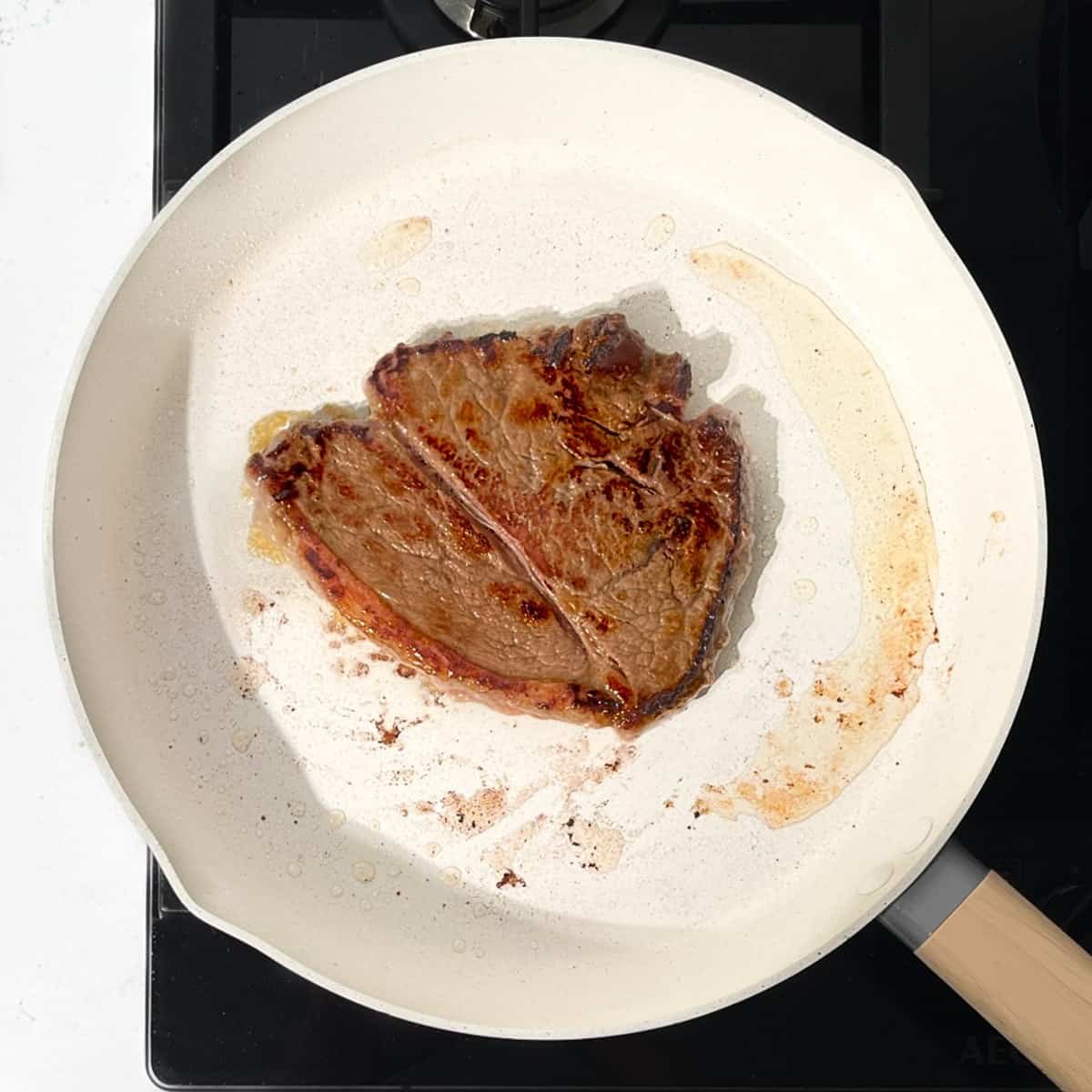 Frying a steak for the prego rolls in a frying pan.