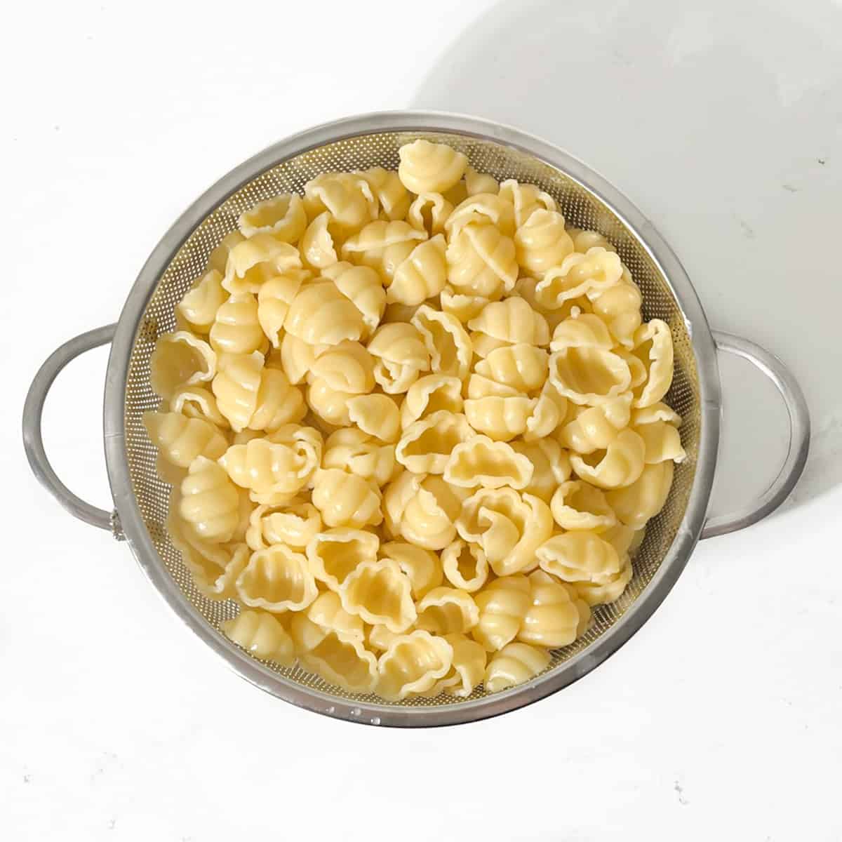 Pasta draining in a colander.