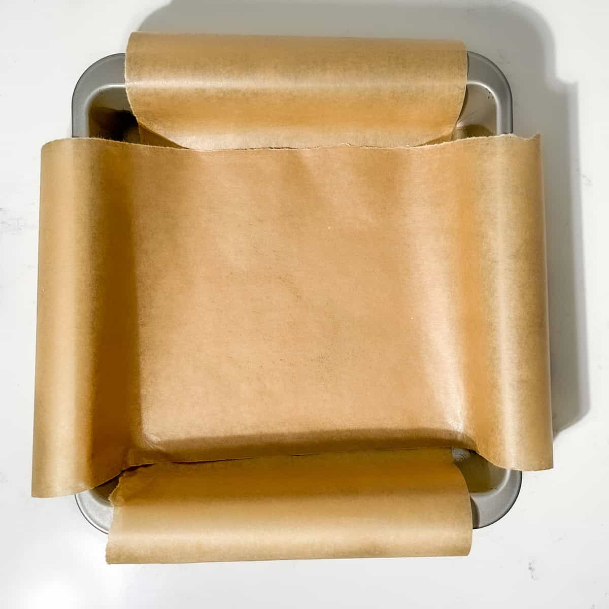 A square pan lined with parchment paper.