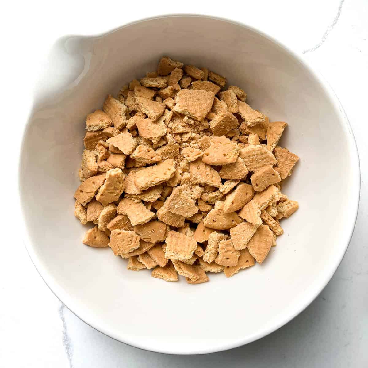 Crushed biscuits in a large white bowl.