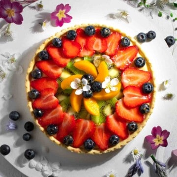 Tarte aux Fruits on a white board, surrounded by flowers.