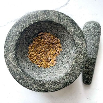 Adding the toasted fennel and cardamom seeds tp a mortar and pestle.