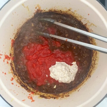 Adding the tomatoes and leftover marinade to the onion mixture in a large saucepan.